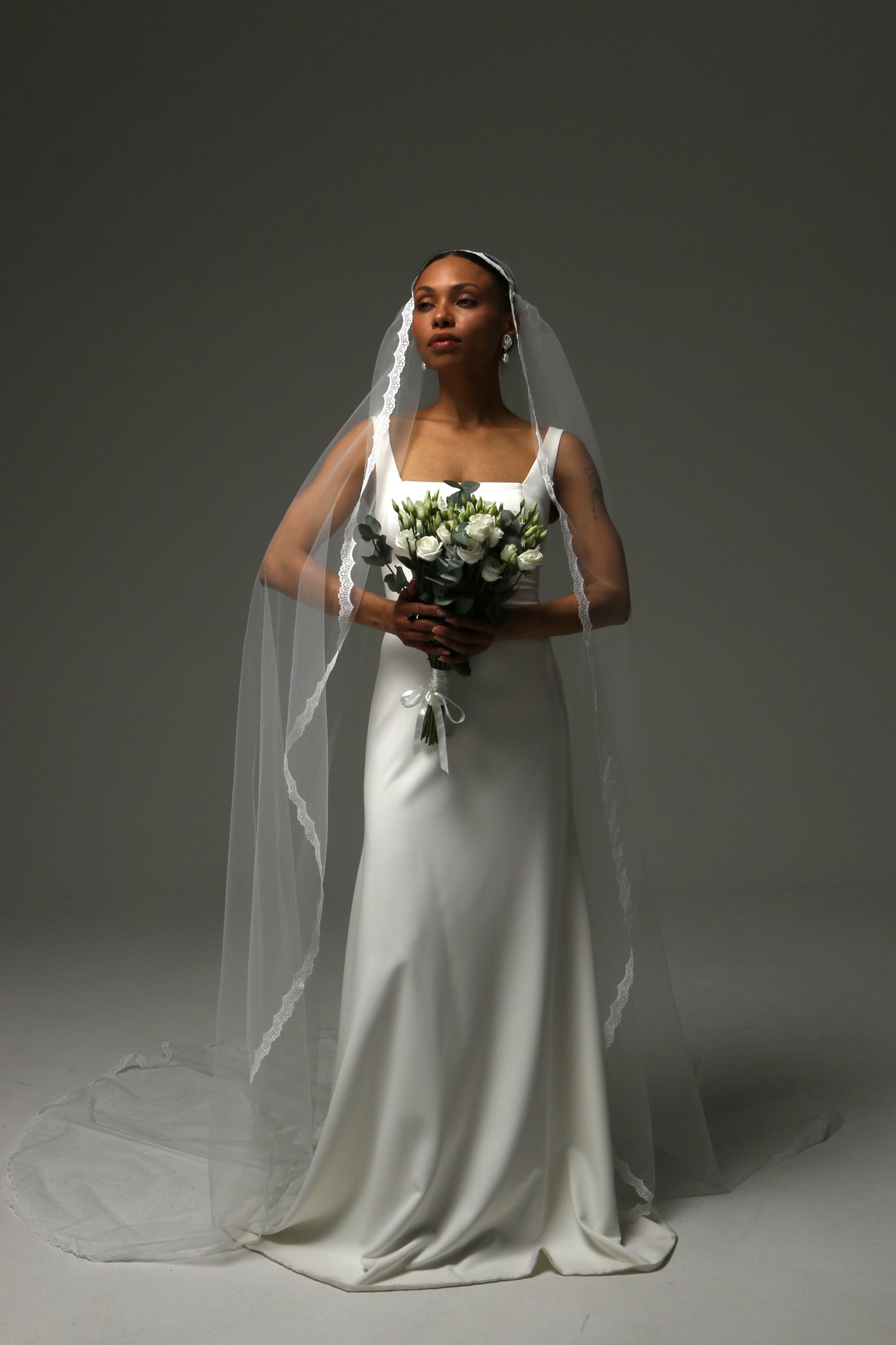 Long cathedral veil with soft drape and refined lace border.