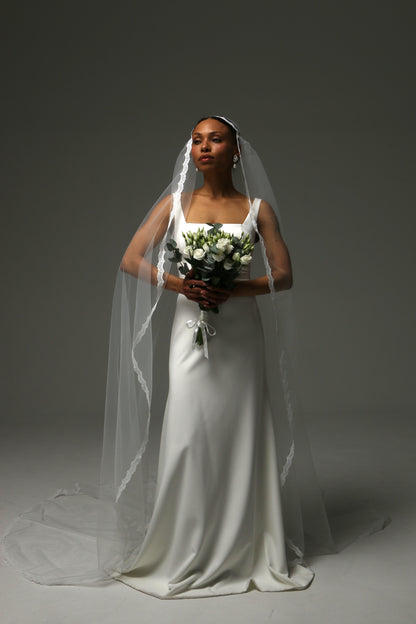 Long cathedral veil with soft drape and refined lace border.