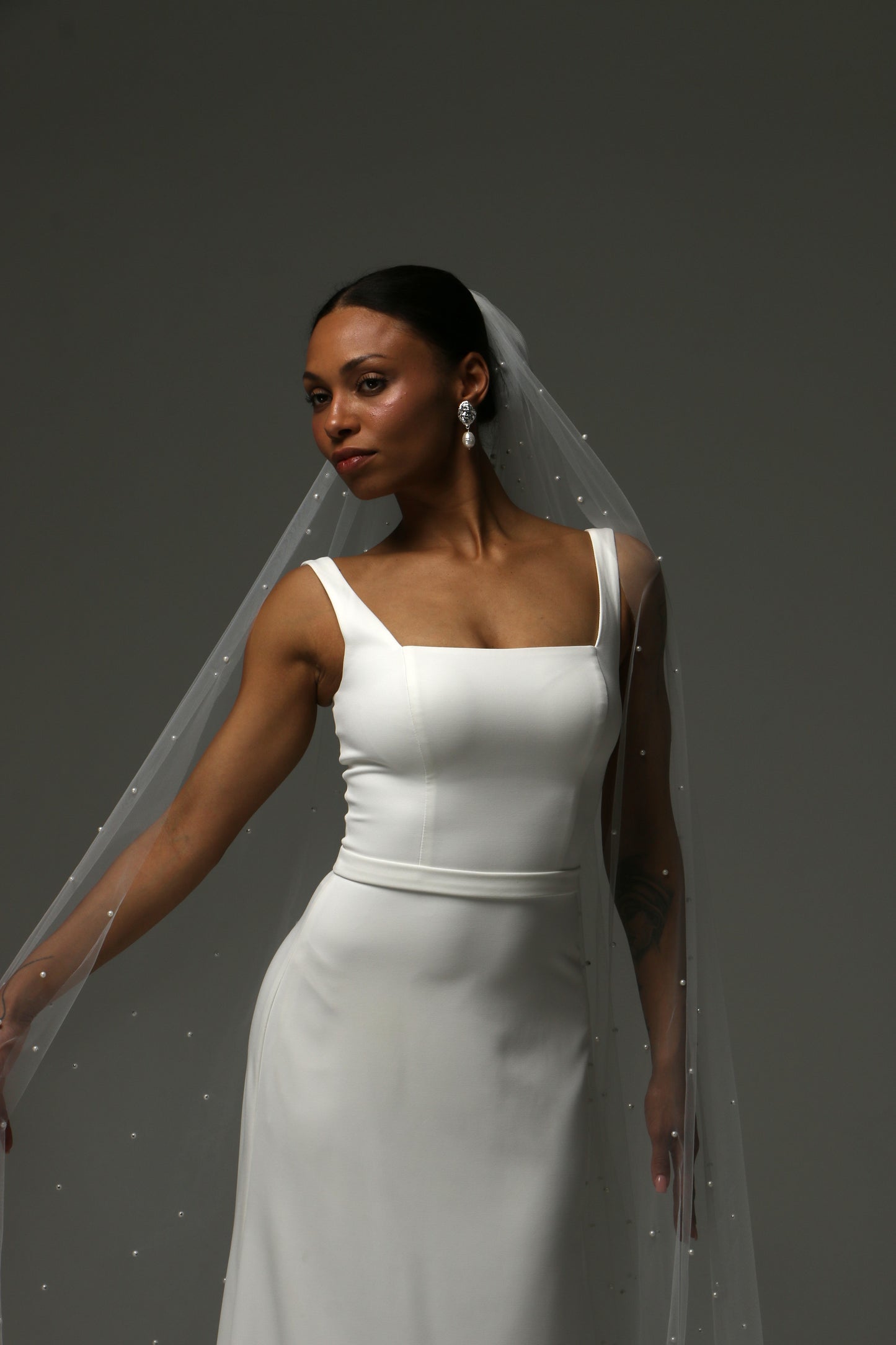 Minimalist bridal veil with subtle pearl detailing and cathedral train.
