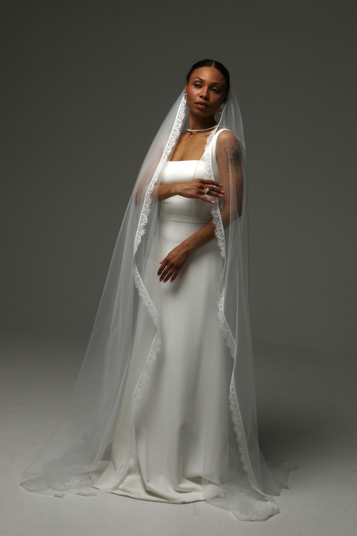 Modern bridal look featuring a cathedral-length lace edge veil.