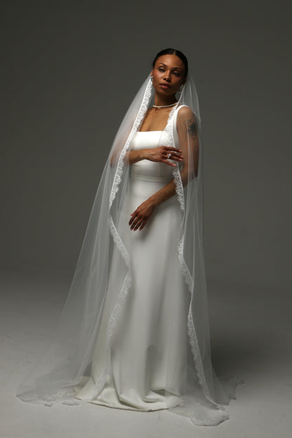 Modern bridal look featuring a cathedral-length lace edge veil.