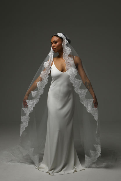 ride wearing a cathedral-length mantilla veil with intricate lace border.