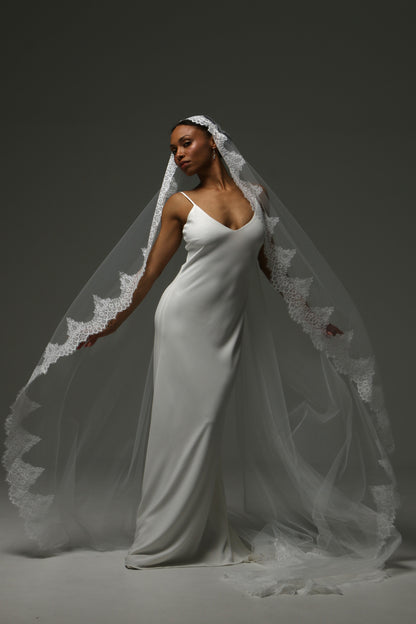 Bride posing in a cathedral mantilla veil with ornate lace detailing.