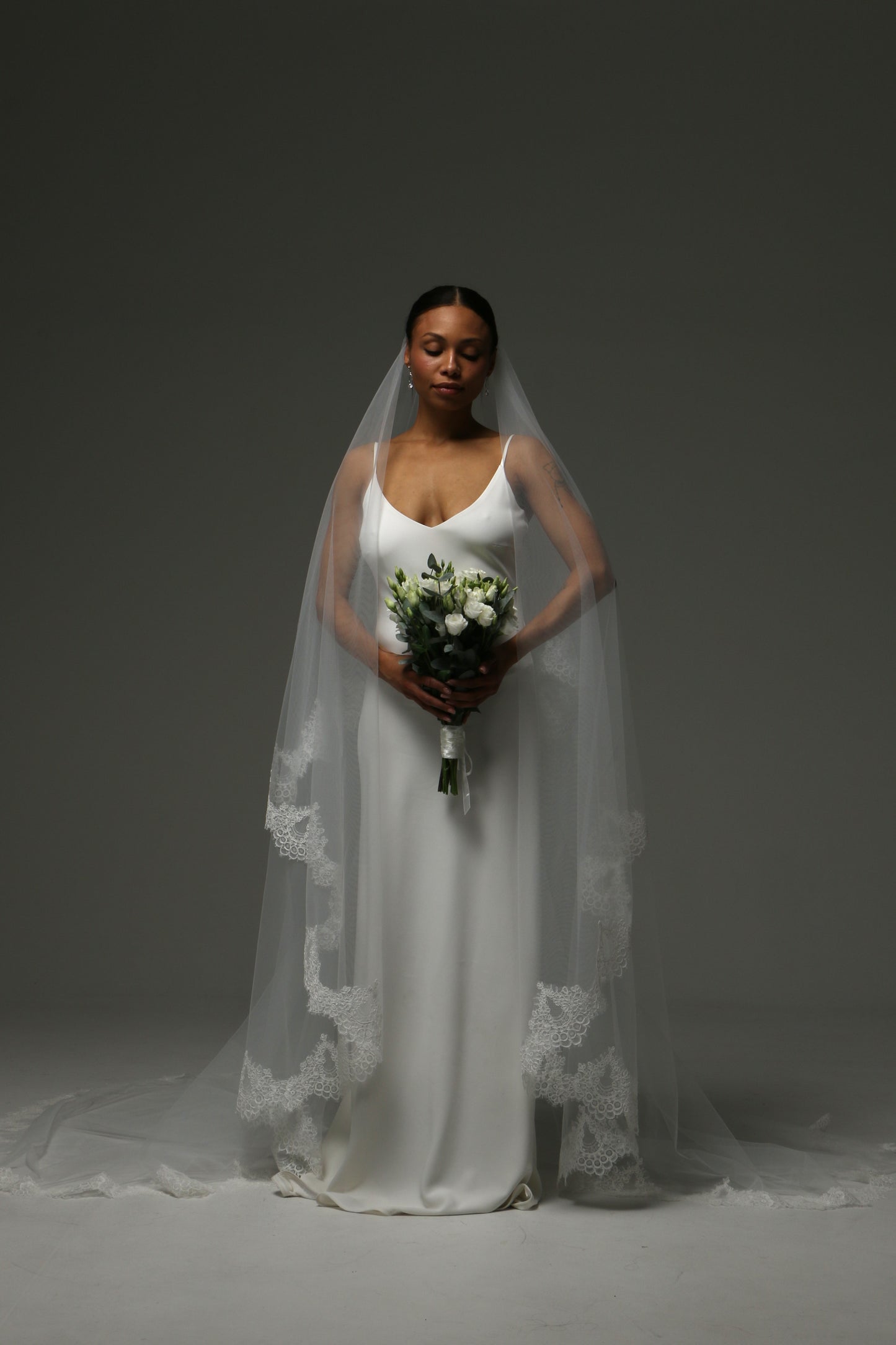 Two-tier cathedral wedding veil with blusher and wide lace edge.