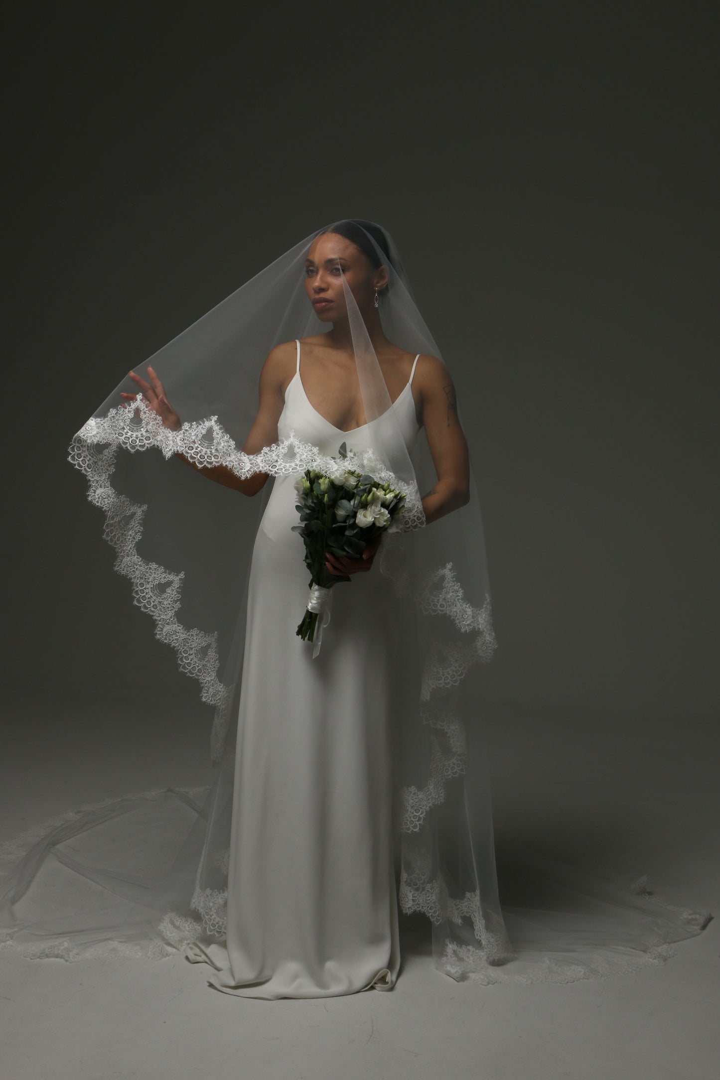 Elegant bridal veil with wide lace border and flowing silhouette.