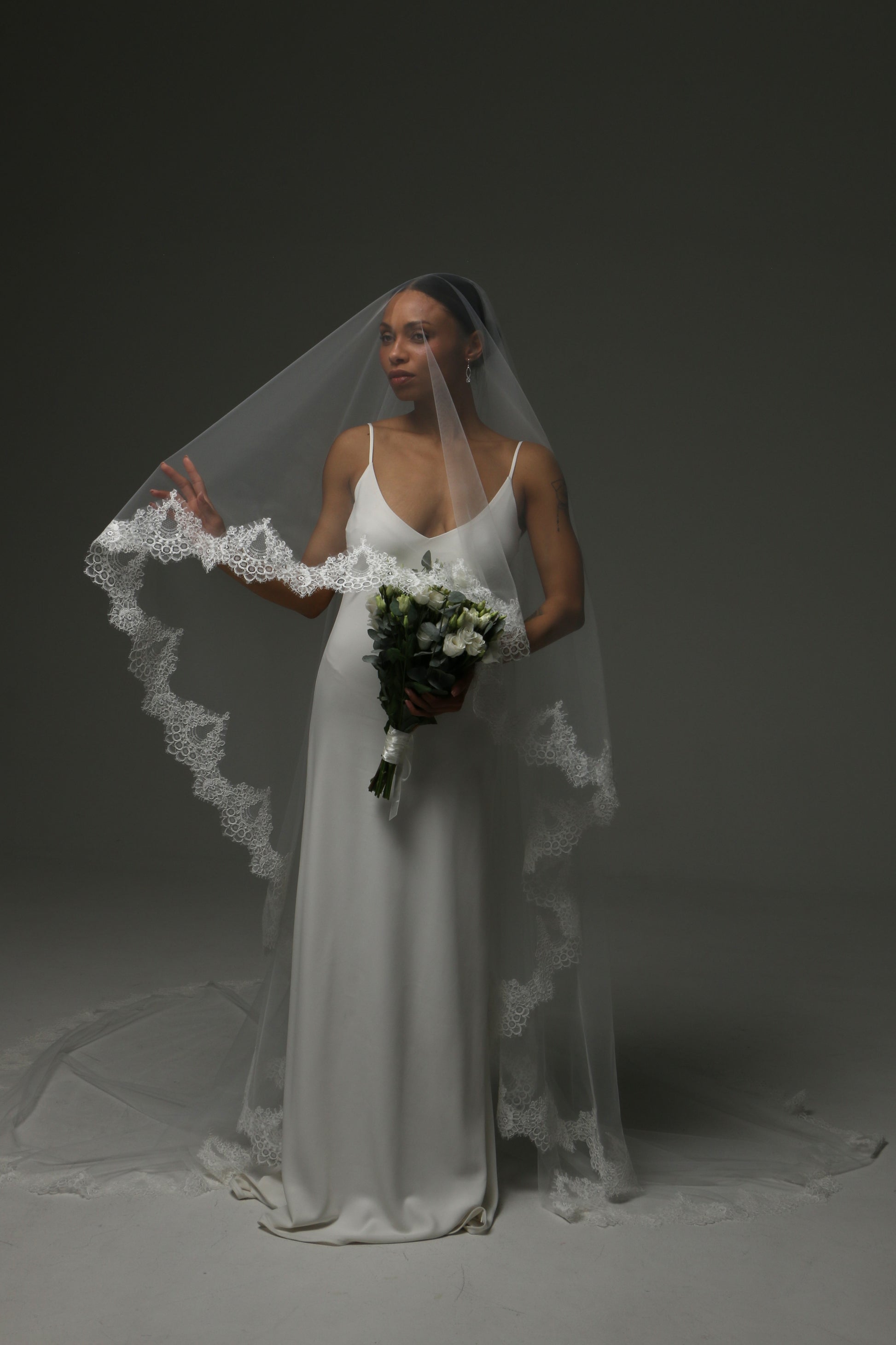 Elegant bridal veil with wide lace border and flowing silhouette.