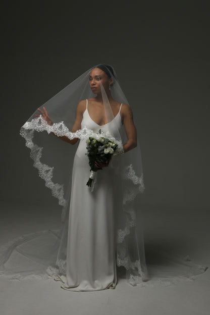 Elegant bridal veil with wide lace border and flowing silhouette.