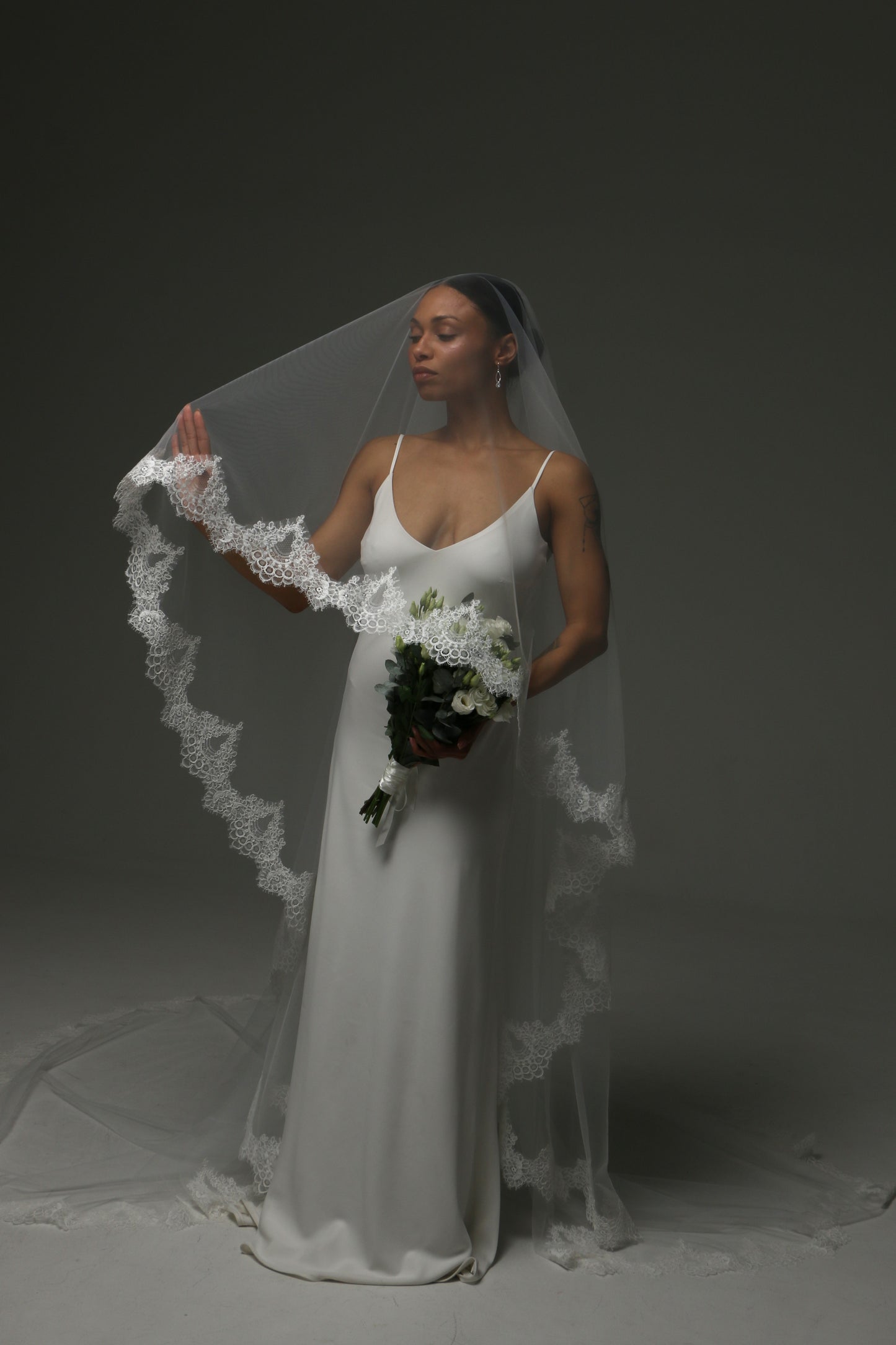 Cathedral-length veil with decorative lace trim framing the bride.