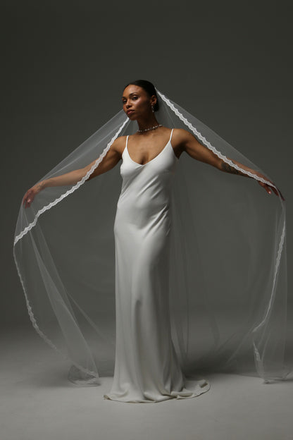 One-tier cathedral wedding veil with thin lace edge and soft illusion tulle.