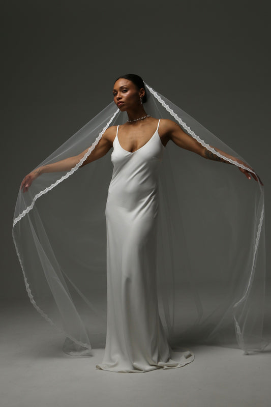 One-tier cathedral wedding veil with thin lace edge and soft illusion tulle.