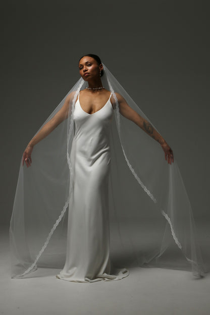 Bride wearing a one-tier cathedral veil with delicate lace edging.