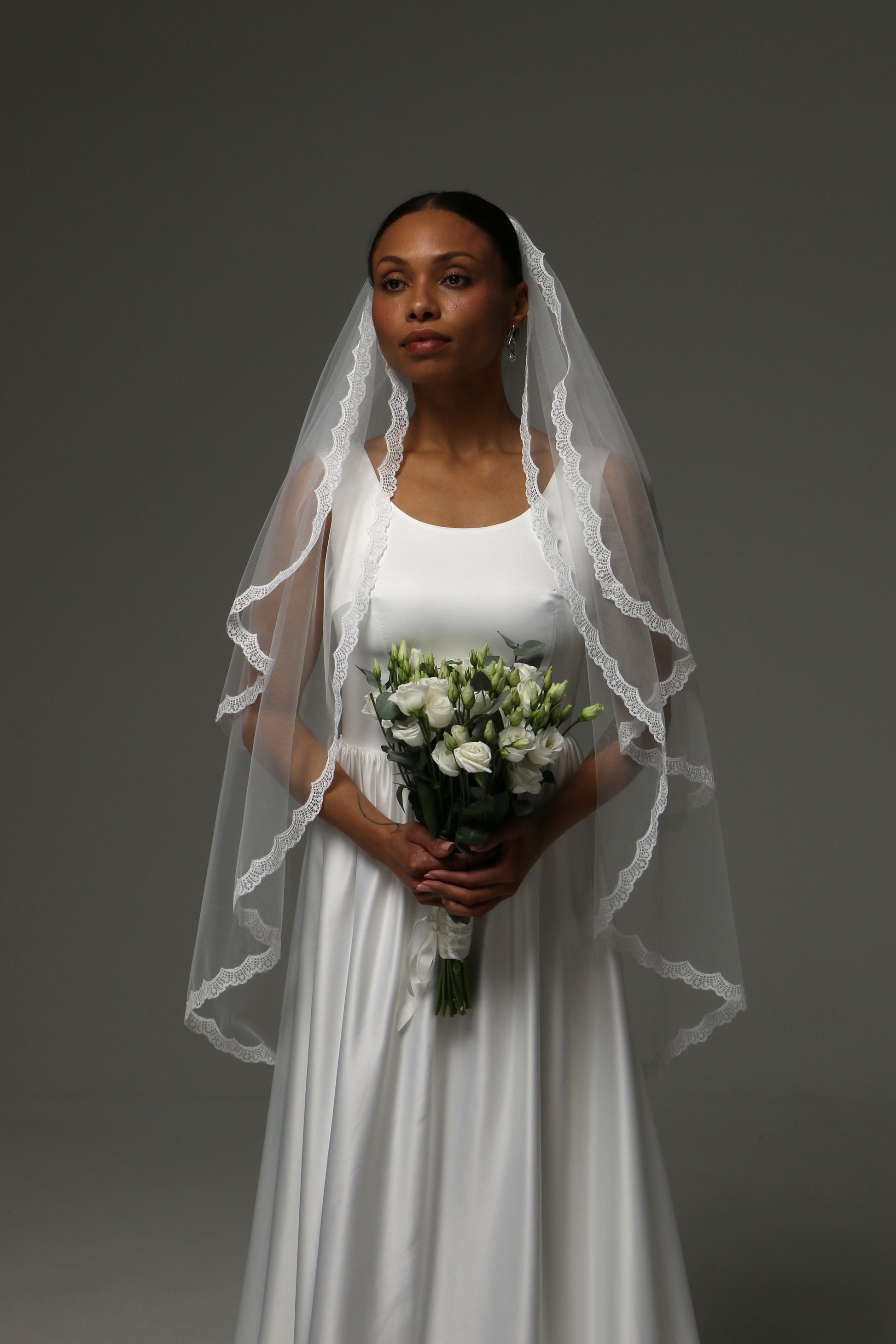 Bride wearing a short bridal veil with thin lace trim.