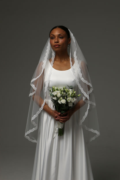 Bride wearing a short bridal veil with thin lace trim.