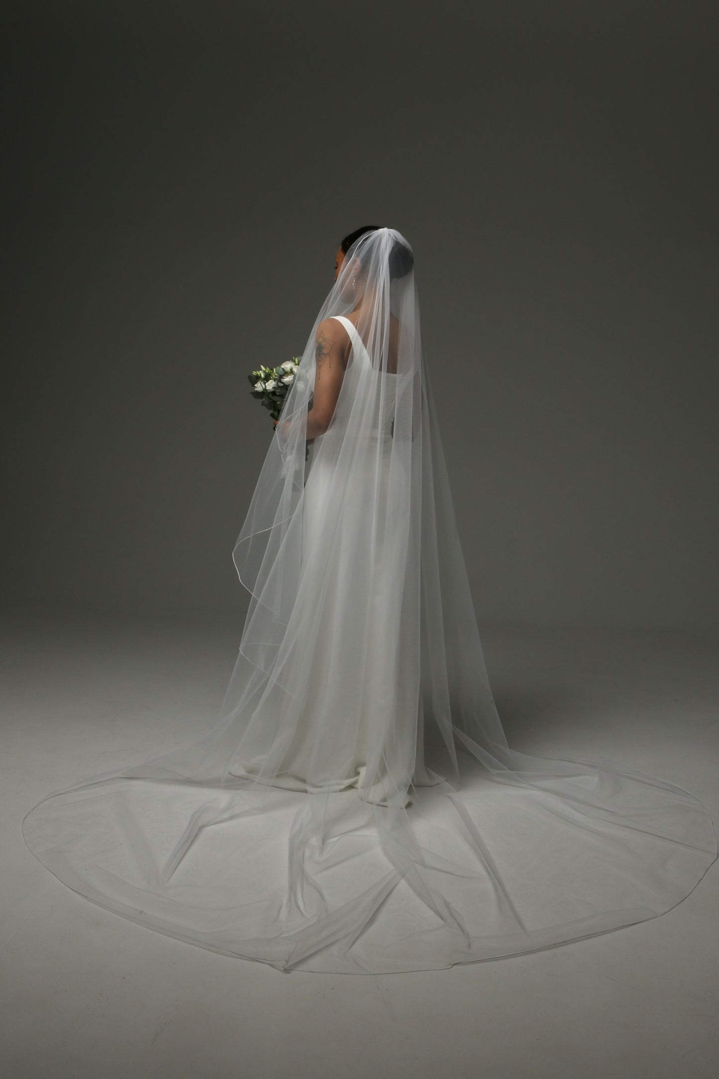 Bride wearing a one-tier cascade veil with subtle pencil trim.
