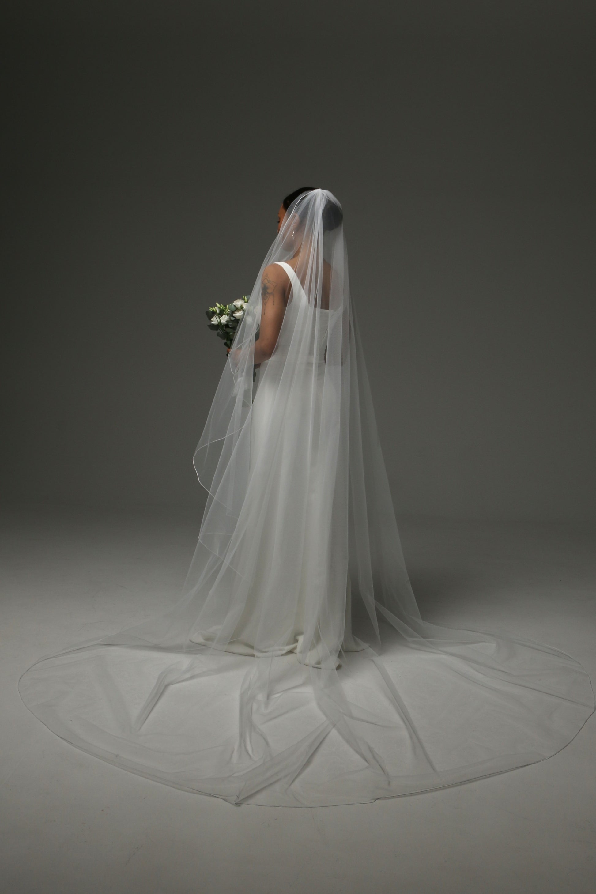 Bride wearing a one-tier cascade veil with subtle pencil trim.