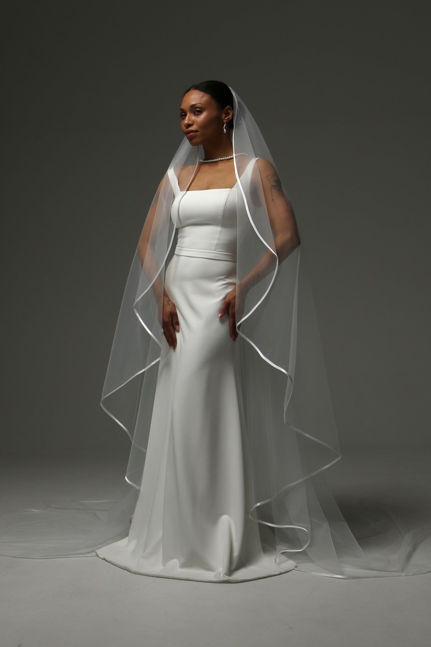 Cathedral-length bridal veil featuring delicate satin trim.