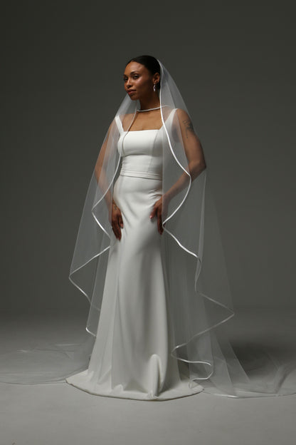 Cathedral-length bridal veil featuring delicate satin trim.