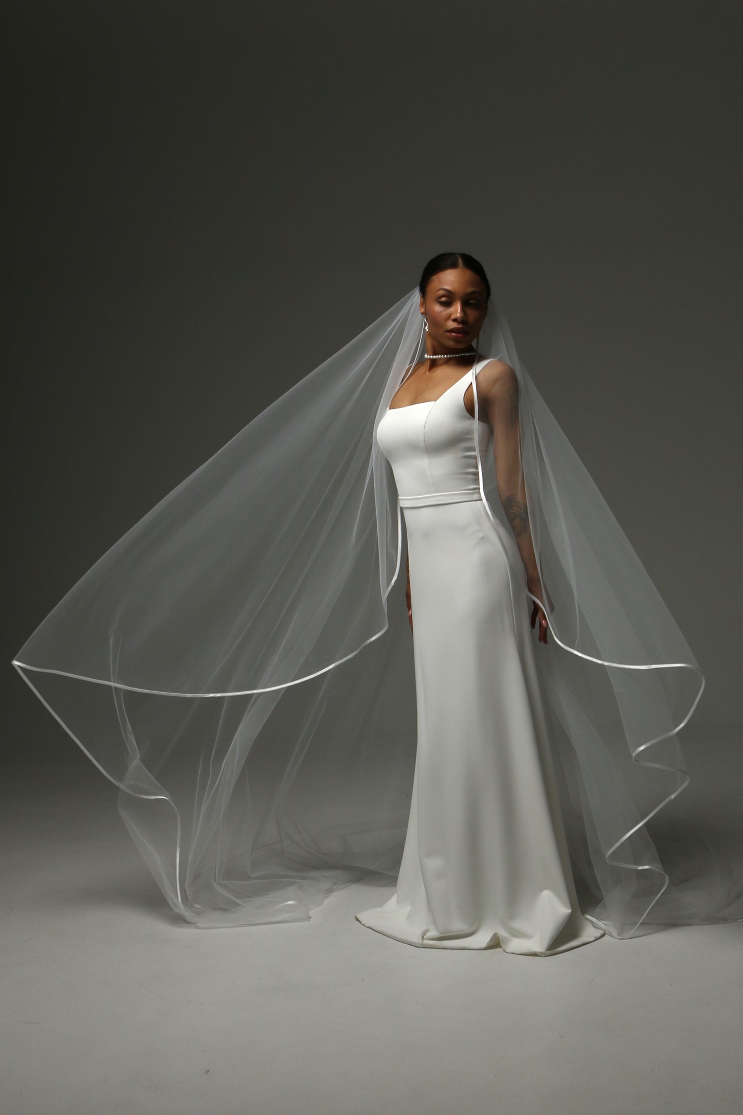 Bride wearing a cathedral veil with refined satin edge finish.