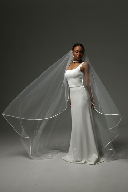 Bride wearing a cathedral veil with refined satin edge finish.