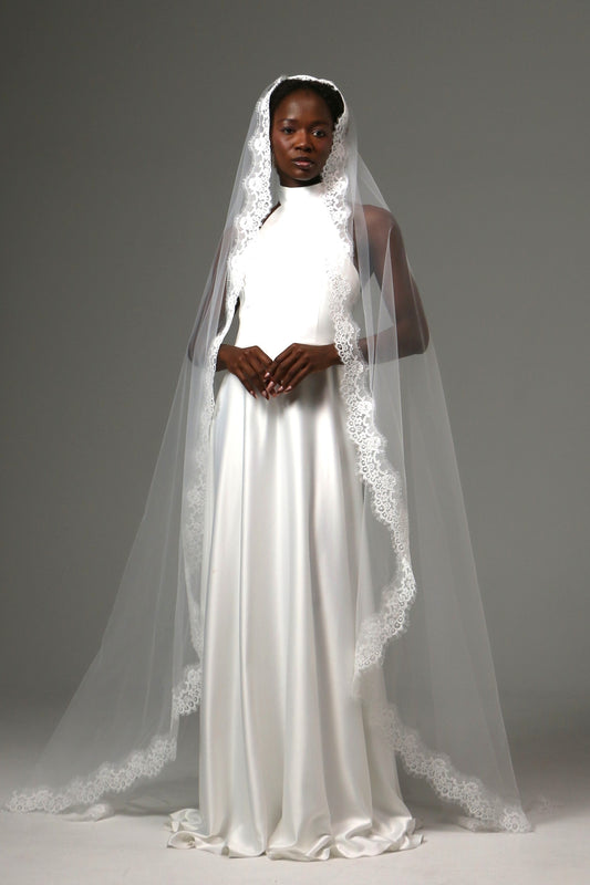Bride wearing a cathedral-length mantilla veil with delicate lace trim.