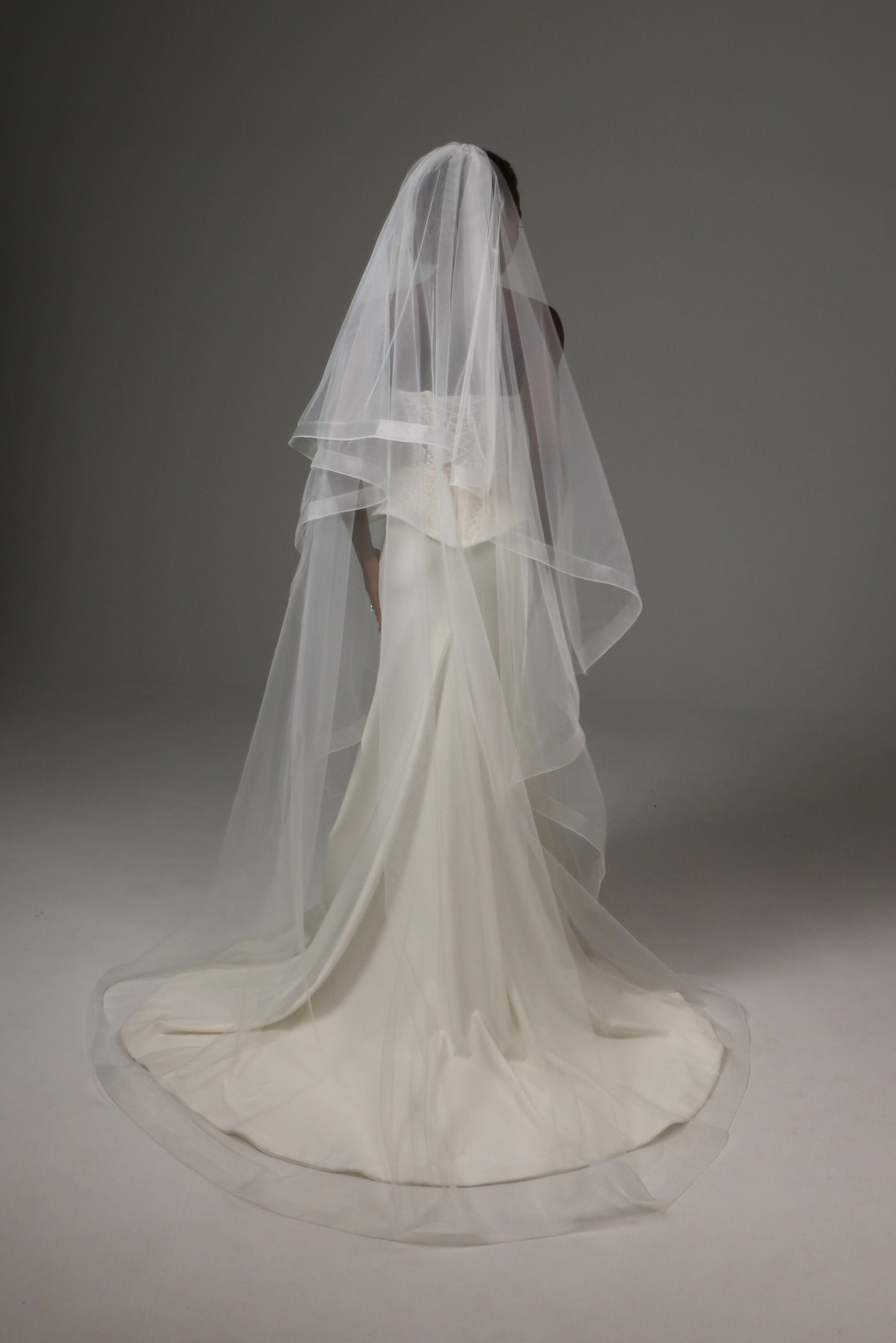 Bride wearing a two-tier veil with flowing cathedral train.