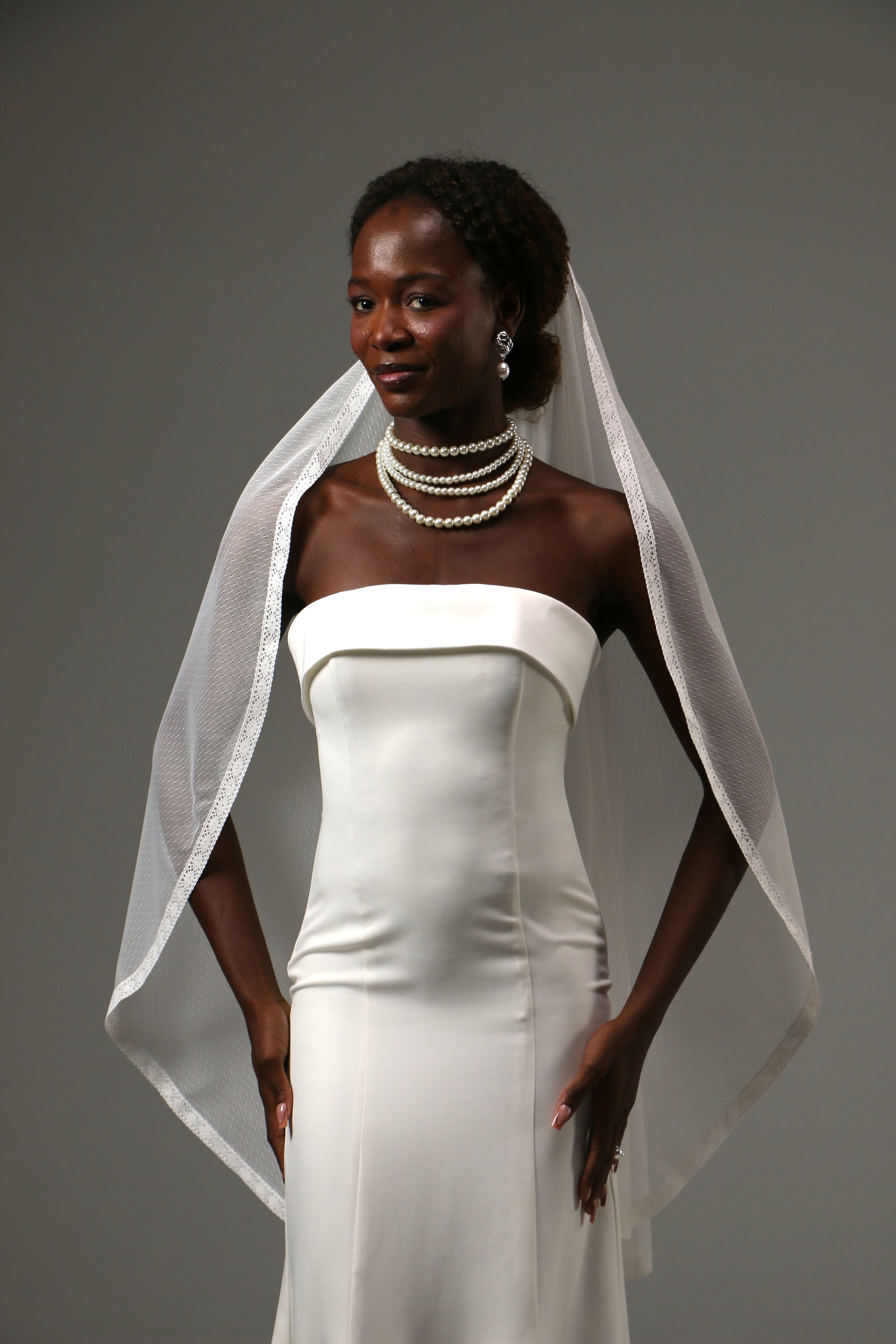 One-tier fingertip wedding veil with dotted tulle and lace edge.