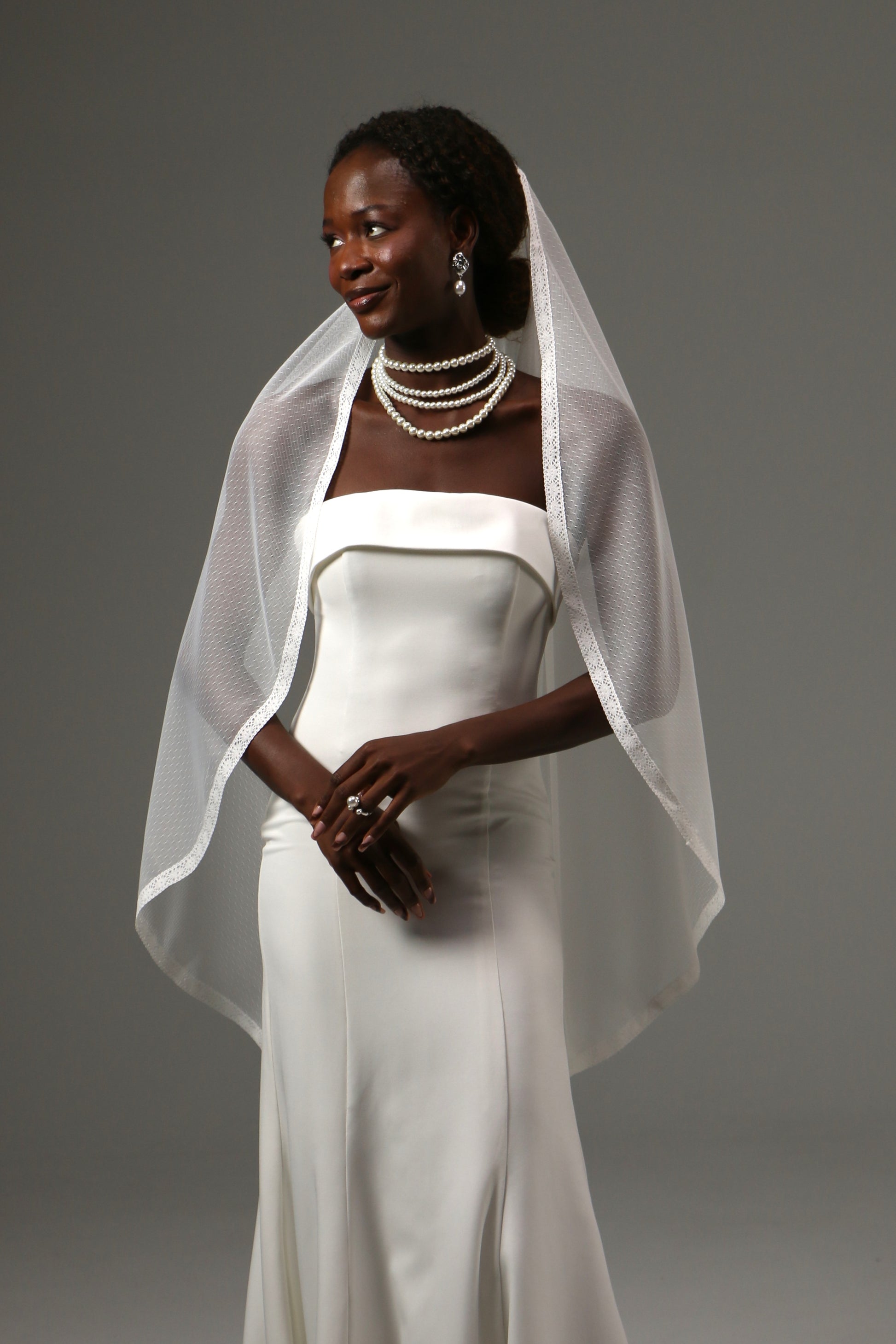 Fingertip bridal veil featuring romantic dotted texture and lace edging.