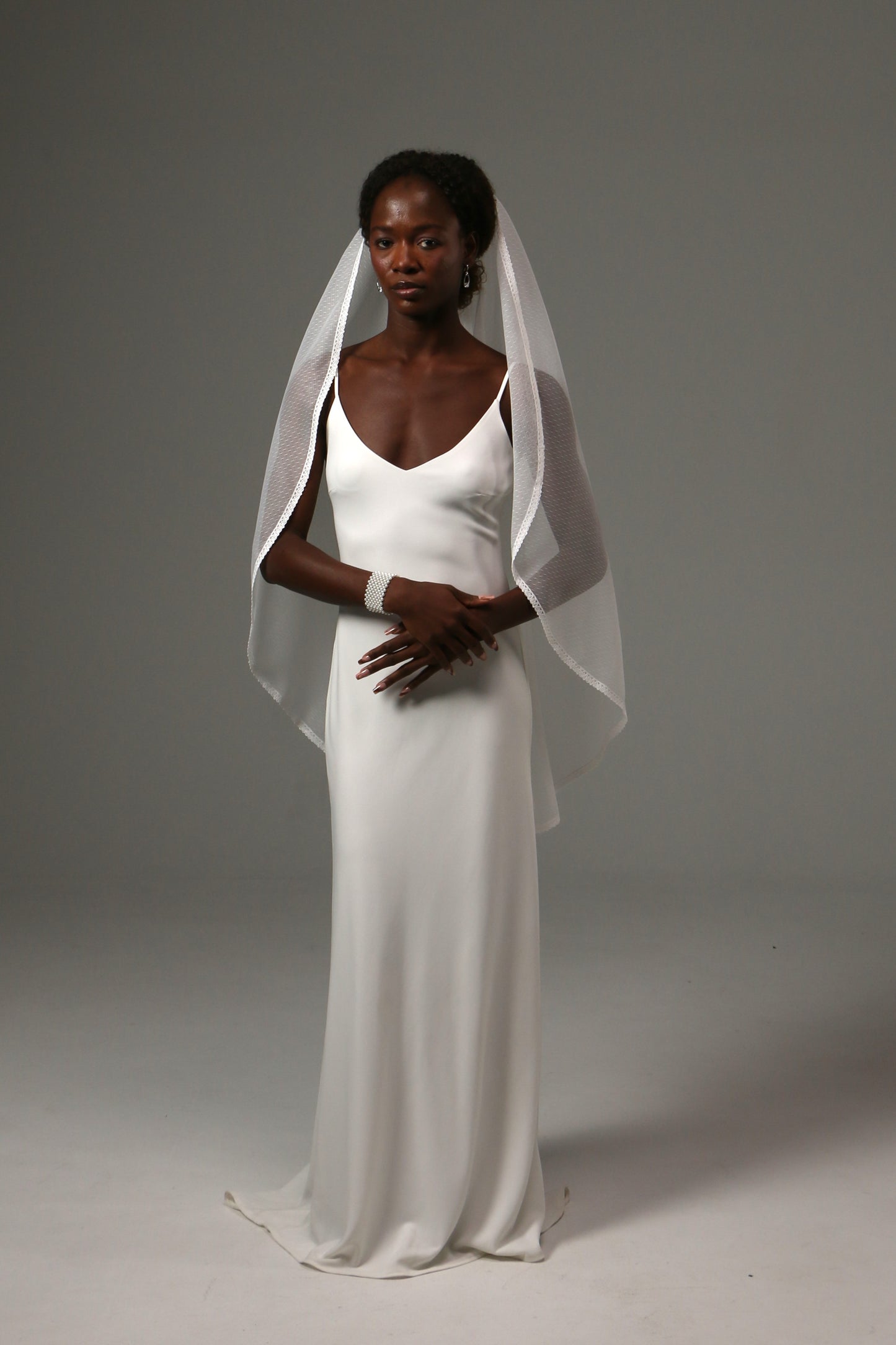 Bride wearing a soft dotted tulle veil with elegant lace trim.