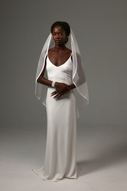 Bride wearing a soft dotted tulle veil with elegant lace trim.