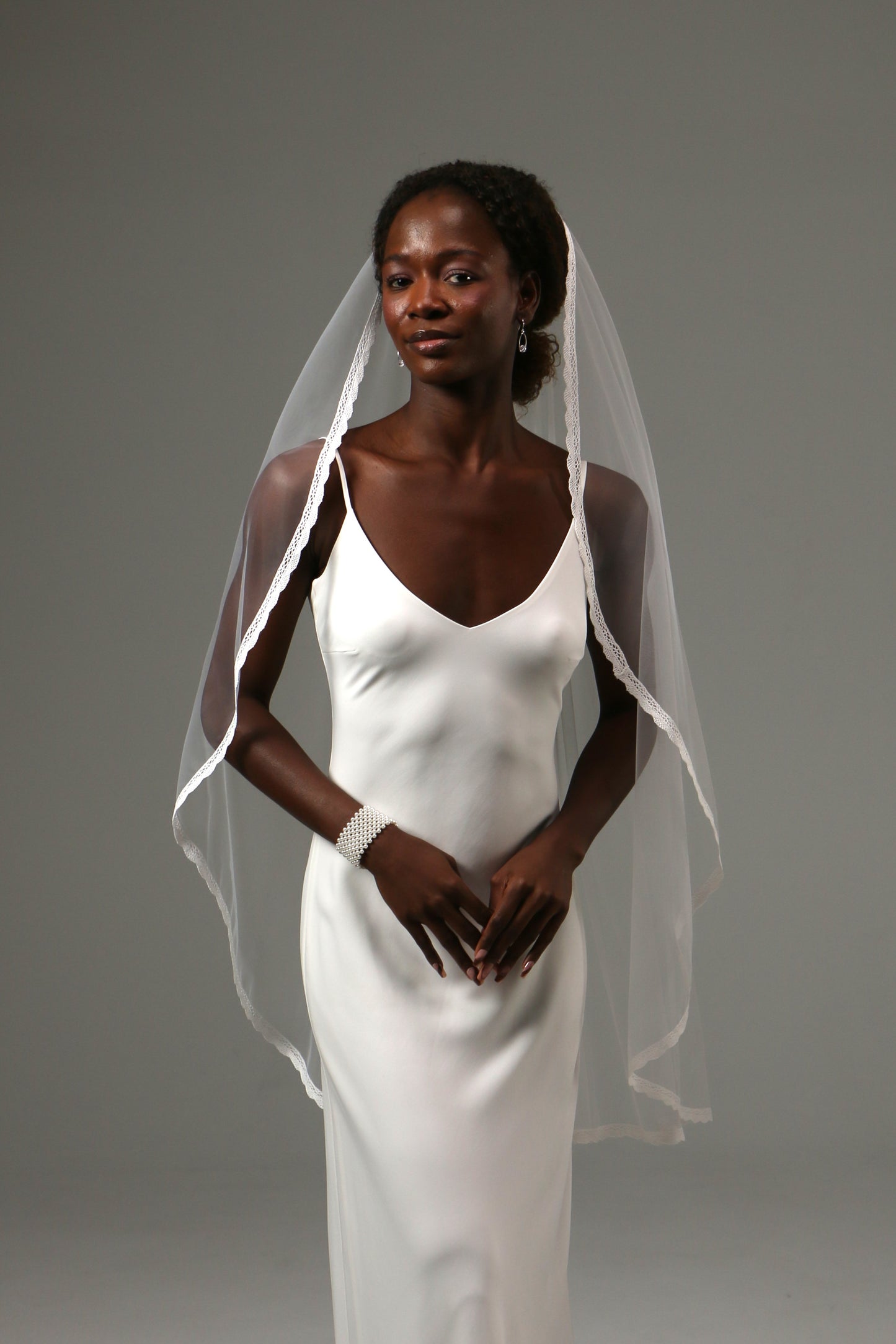 Bride wearing a soft tulle fingertip veil with lace edging.