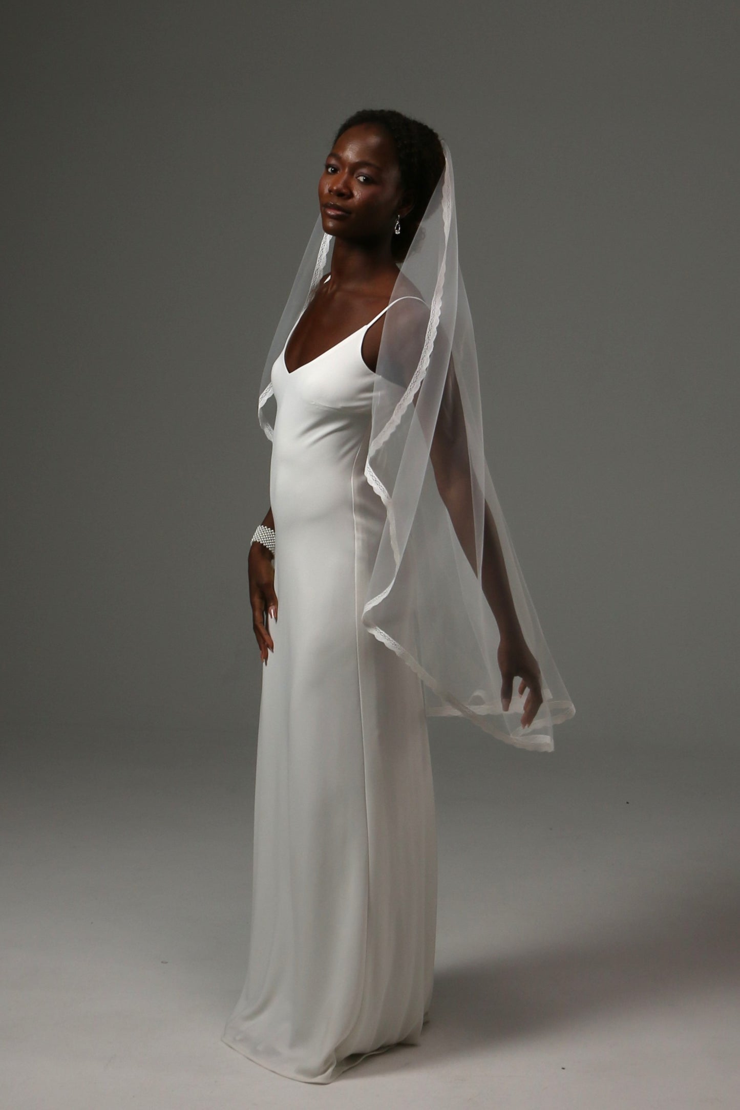 One-tier bridal veil paired with a sleek satin wedding gown.