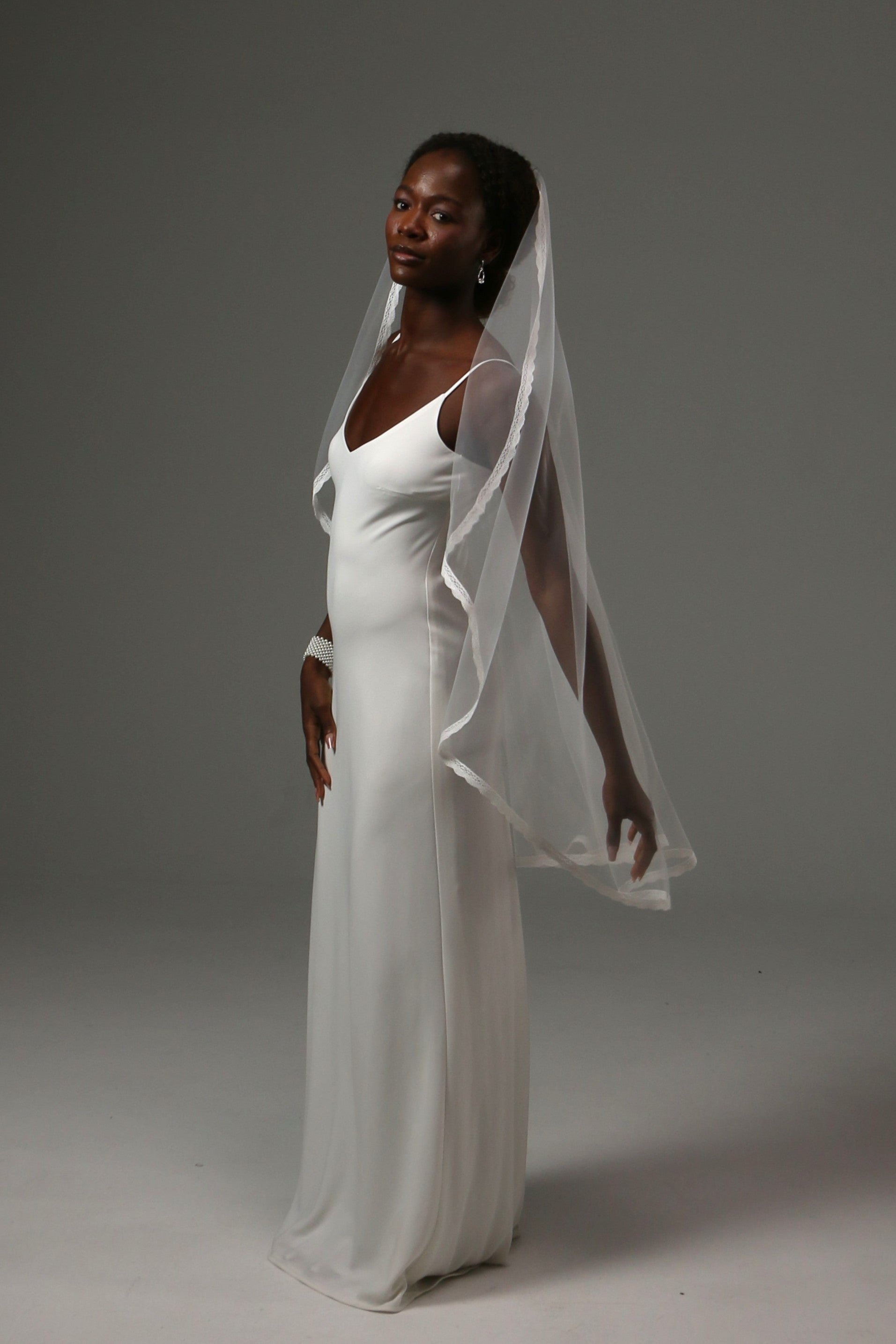 One-tier bridal veil paired with a sleek satin wedding gown.