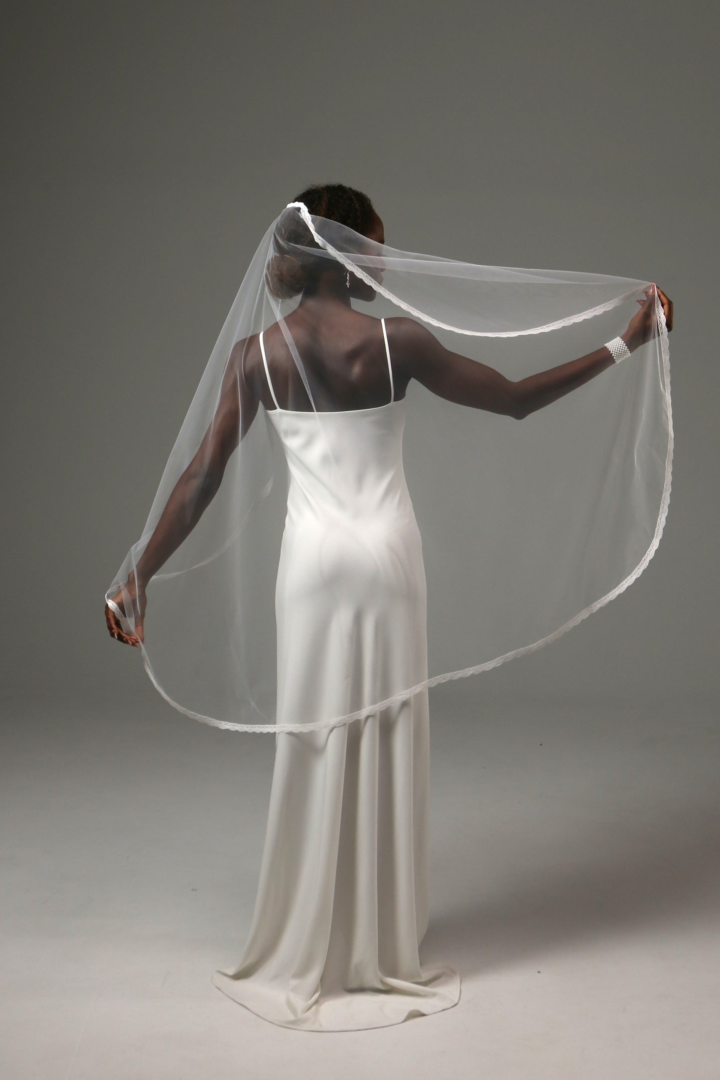 Romantic fingertip-length wedding veil with fine lace border.