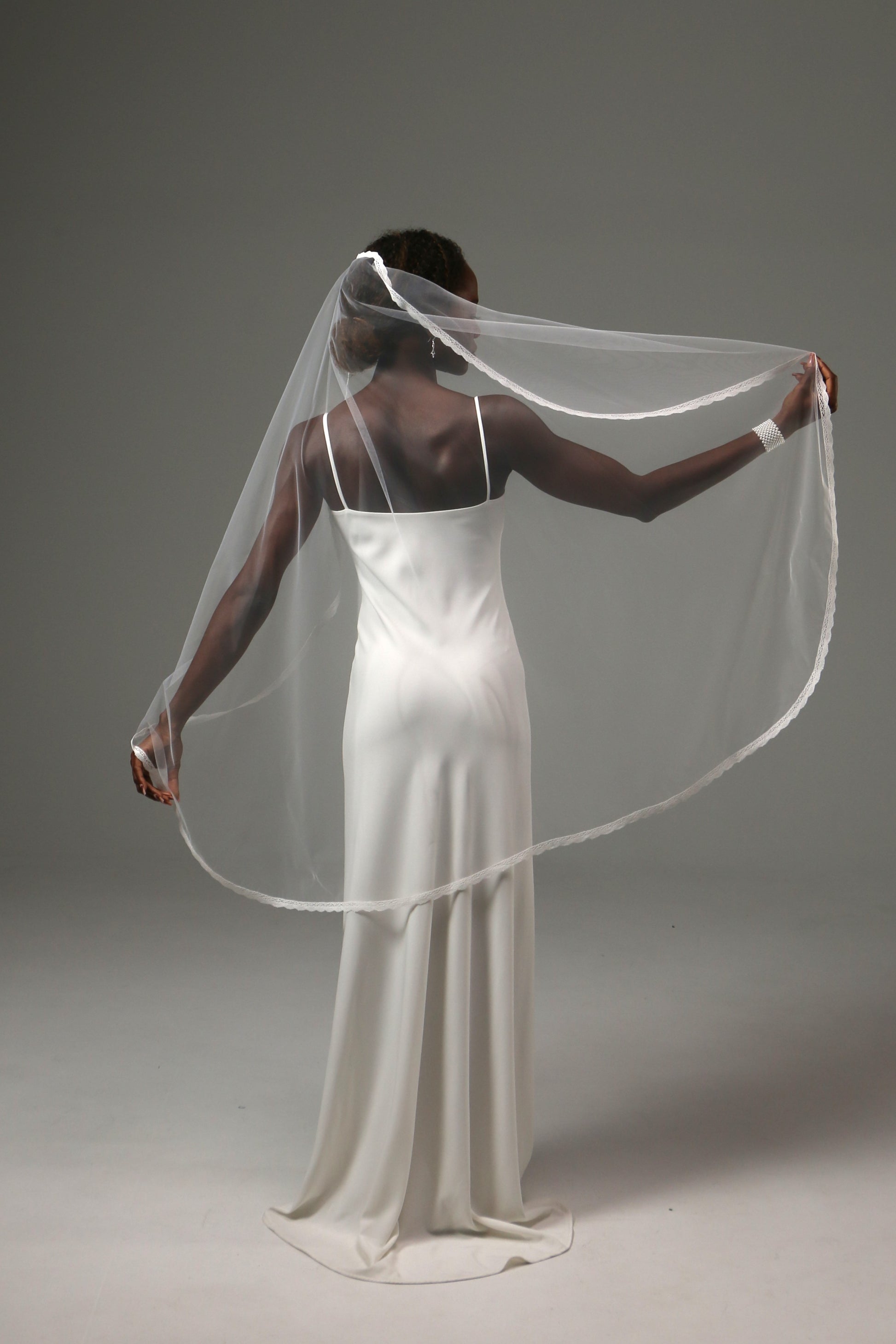 Romantic fingertip-length wedding veil with fine lace border.