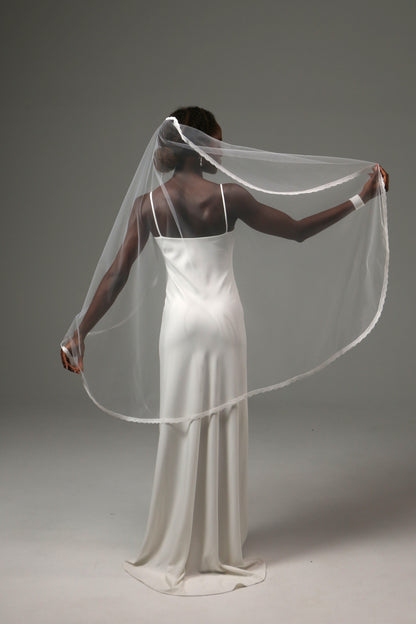 Romantic fingertip-length wedding veil with fine lace border.