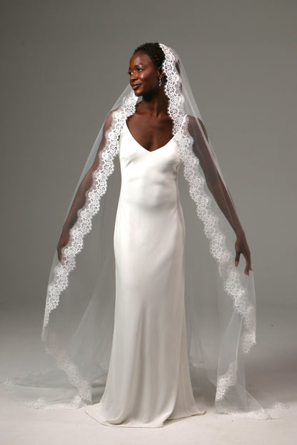 Traditional bridal veil with cathedral train and ornate lace border.